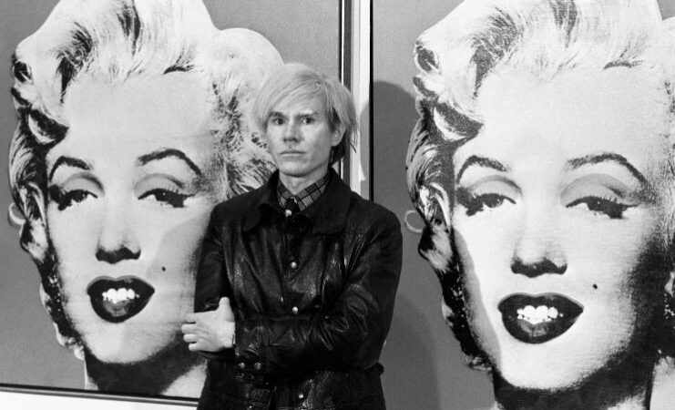 Andy Warhol with two of his paintings of Marilyn Monroe, Tate Millbank, UK, 22 February 1987. PA IMAGES VIA GETTY IMAGES